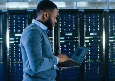 man looking at laptop in server room