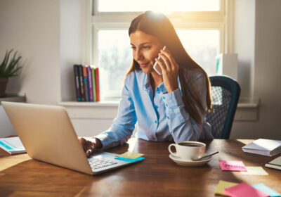 woman on cellphone looking at laptop