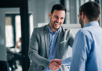 Cheerful young manager handshaking with new employee