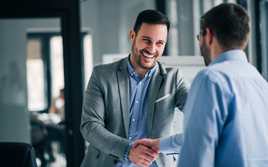 Cheerful young manager handshaking with new employee
