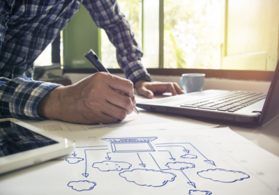 man writing plans at desk